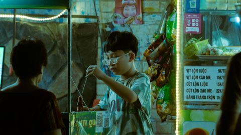 An illuminated street food stall in Vietnam at night, bustling with activity and authentic flavors.