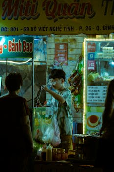 An illuminated street food stall in Vietnam at night, bustling with activity and authentic flavors.