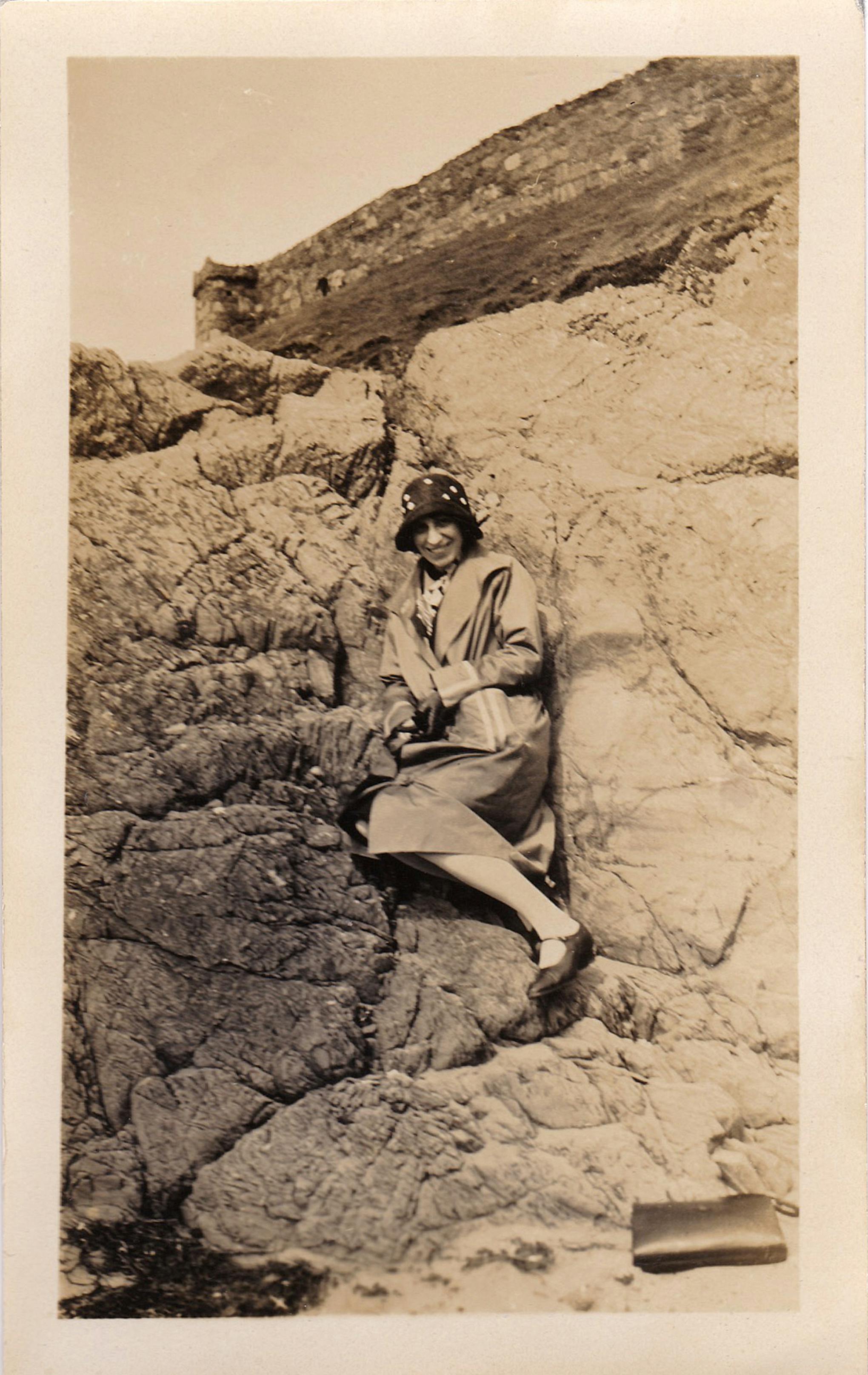 A woman in vintage attire posing on a rugged rock formation, conveying retro charm.