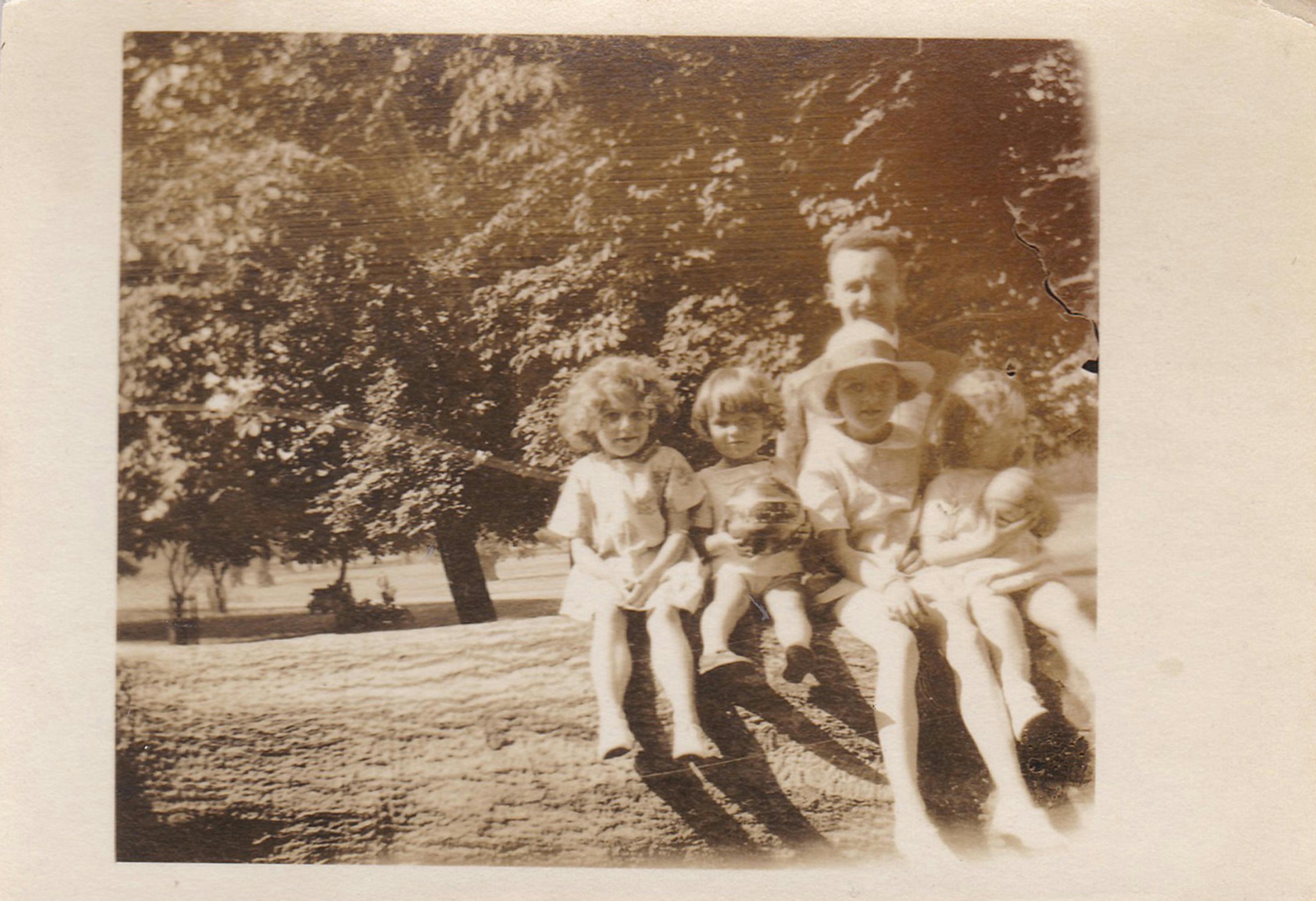 Sepia-toned vintage family photo showing adults and children outdoors.