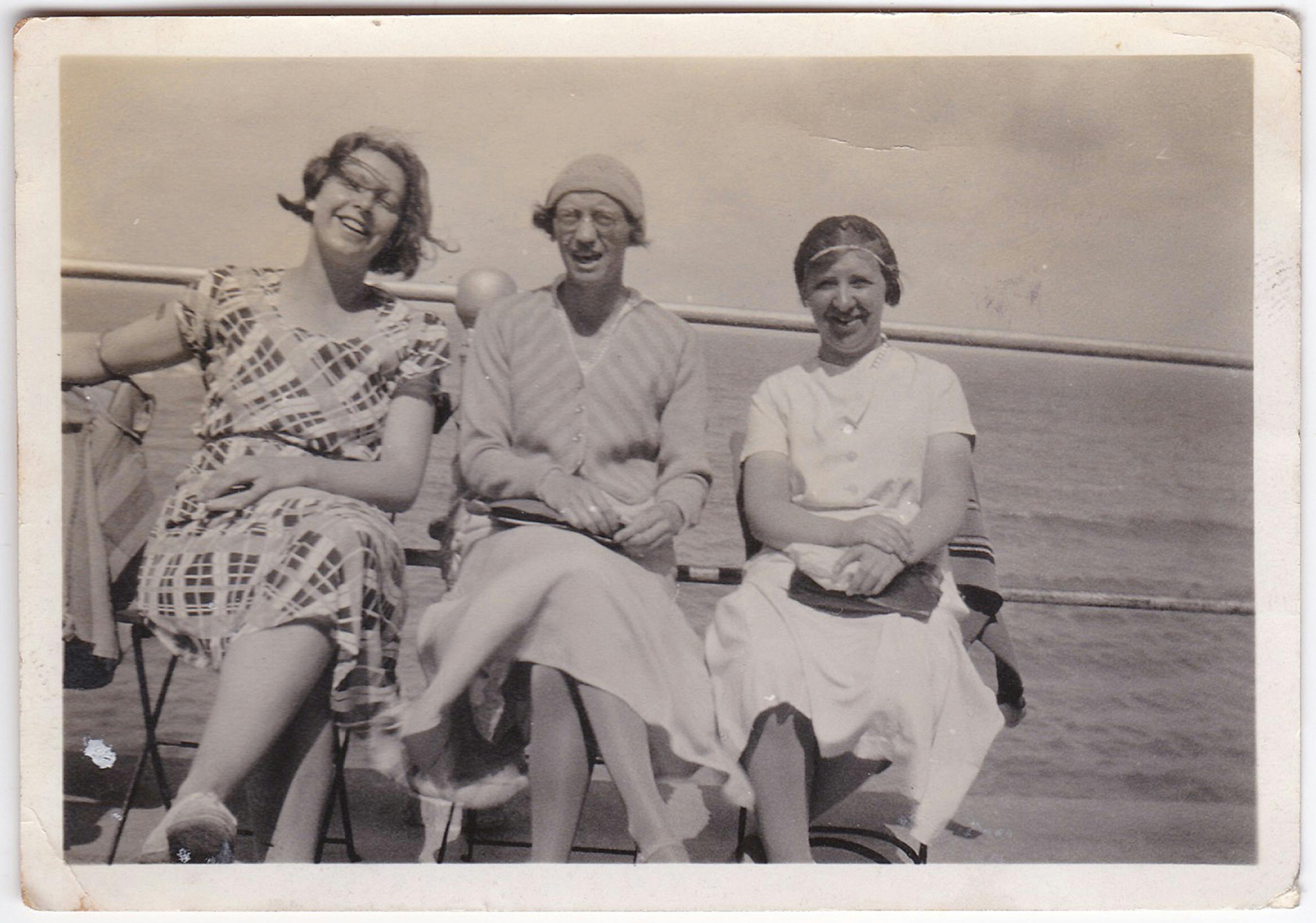 Three women enjoying a seaside trip captured in a vintage style photo.