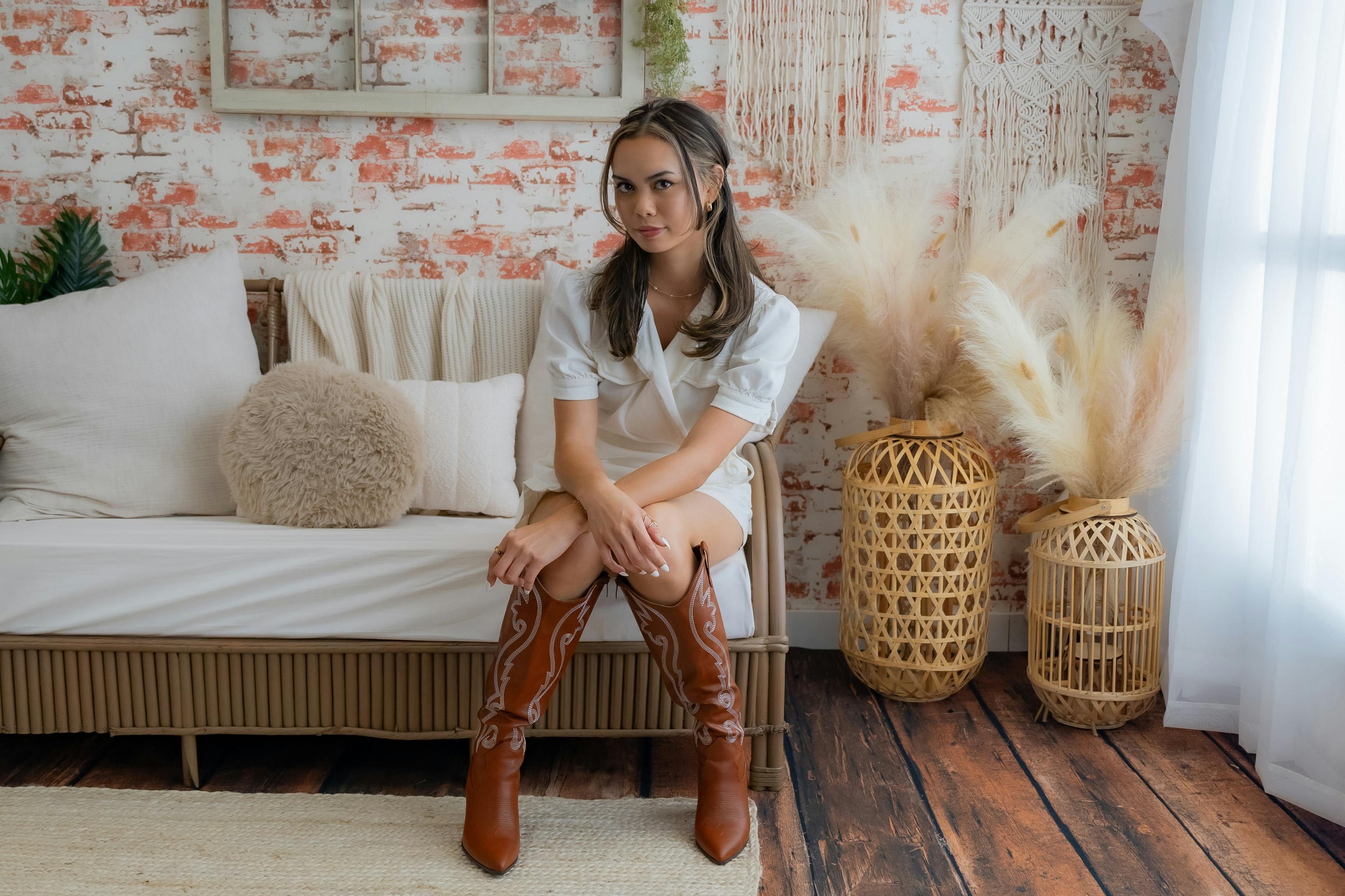 Woman sitting on a couch in a bohemian-style room with rustic decor.