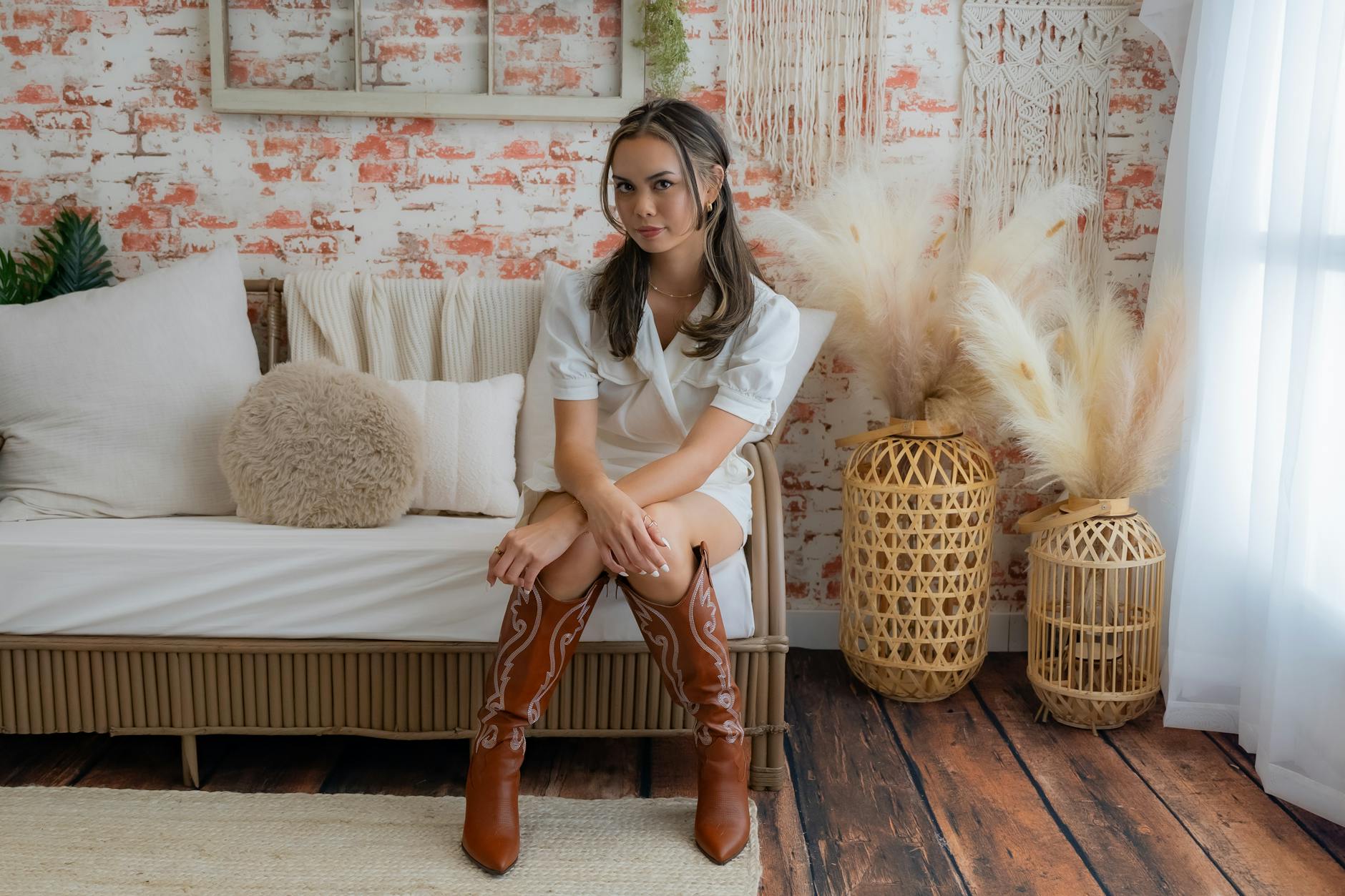 Woman sitting on a couch in a bohemian-style room with rustic decor.