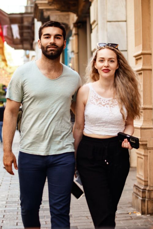 Free Happy couple walking together in an urban street, radiating modern and relaxed vibes. Stock Photo