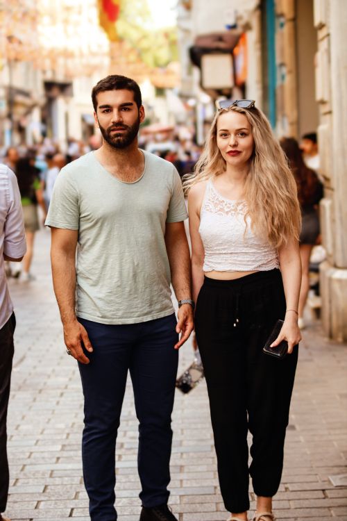 Free Casual stroll of a young couple in a bustling urban street during daytime. Stock Photo