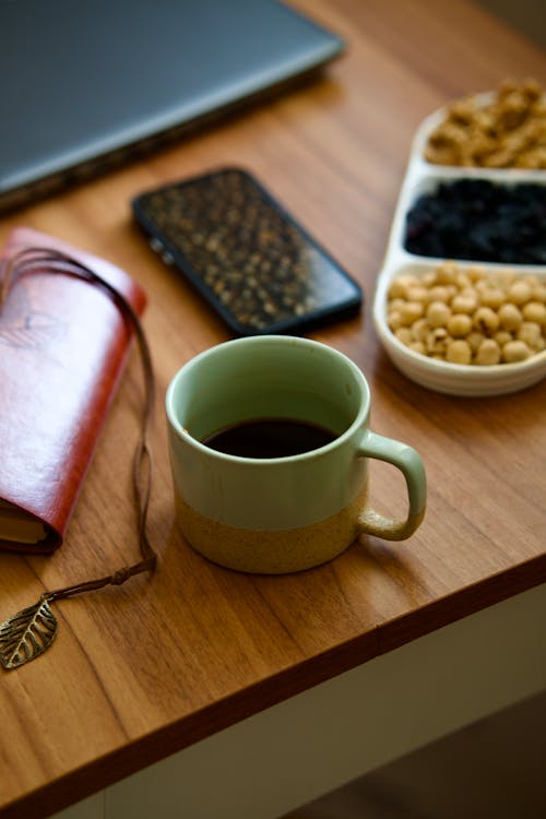 A coffee cup sits on a desk next to a laptop