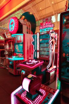 Colorful arcade with neon lights featuring Pink Panther game machines in a lively setting.