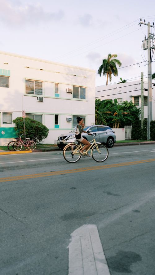 Free A cyclist rides through a sunny urban street, capturing the essence of city life and transportation. Stock Photo