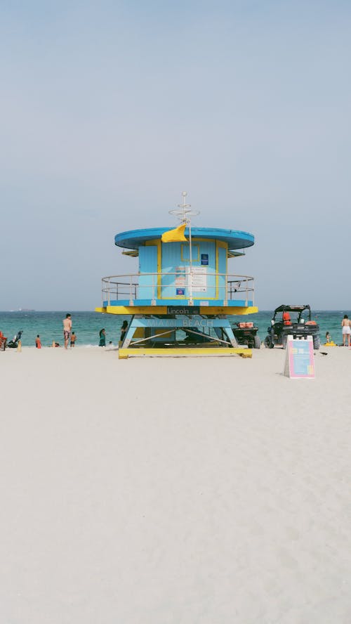 A lifeguard tower on the beach with people walking by