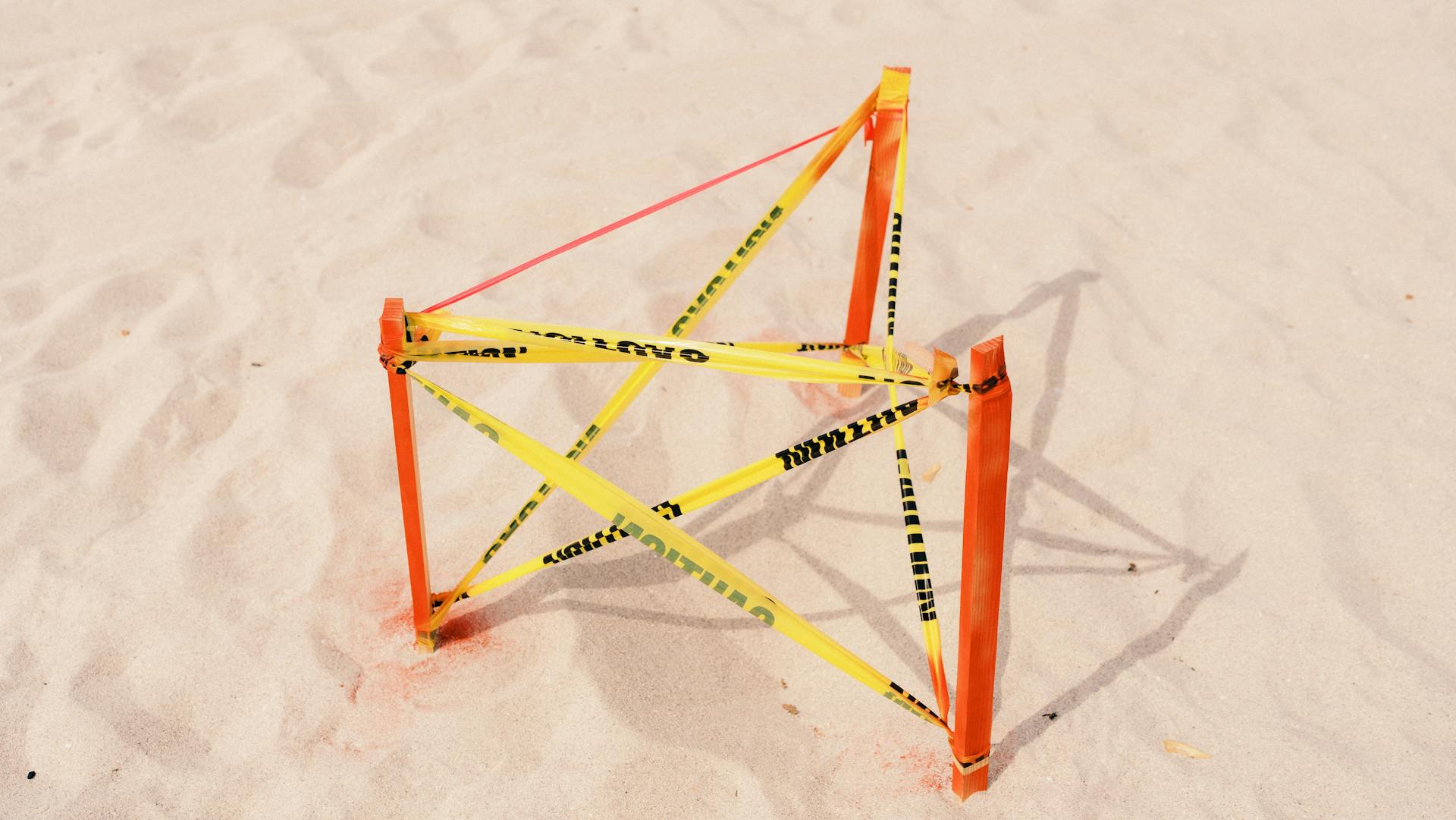 Yellow Tape Hanging between Three Wooden Poles Creating a Pentagram Symbol