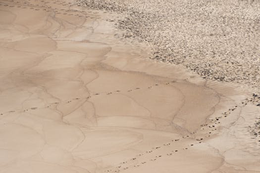 An aerial shot of sandy beach in Portugal with scattered footprints, highlighting natural patterns.