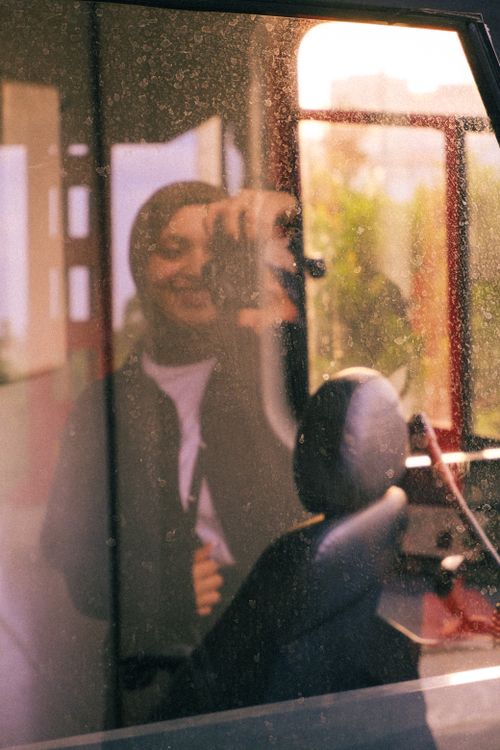 Free Smiling photographer capturing a reflective shot through a dusty window. Stock Photo