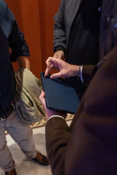 Group of adults in business attire collaborating using a tablet indoors.