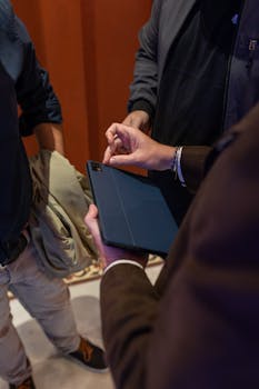 Business professionals collaborating around a tablet device, focused and engaged.