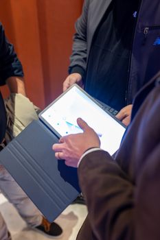 Close-up of people using a tablet with touchscreen interaction in an indoor setting.