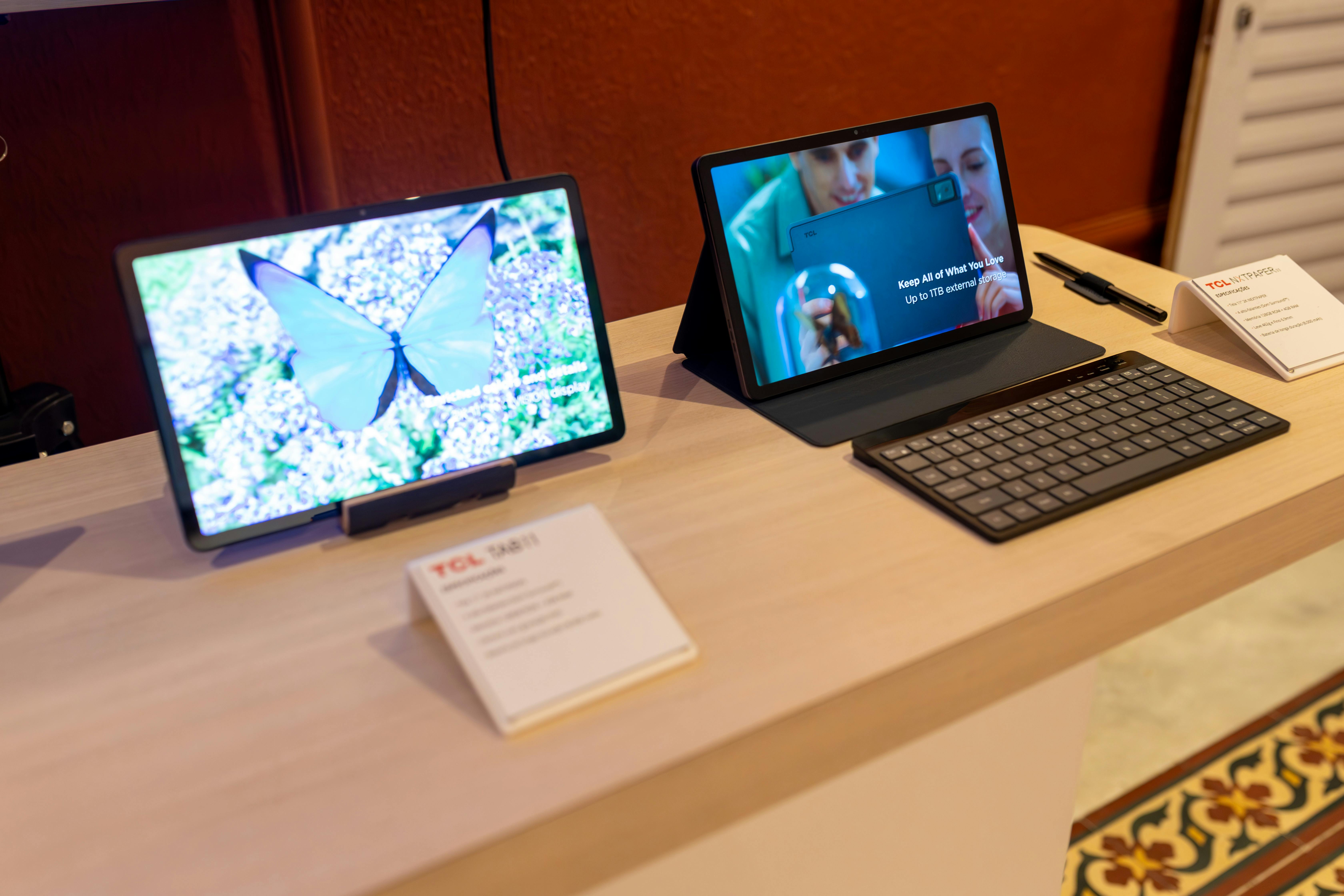 Two sleek tablets showcased with a keyboard in a technology showroom, highlighting wireless connectivity.