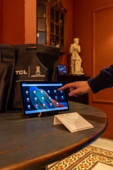 A person demonstrates a touchscreen tablet on a table, highlighting modern technology indoors.