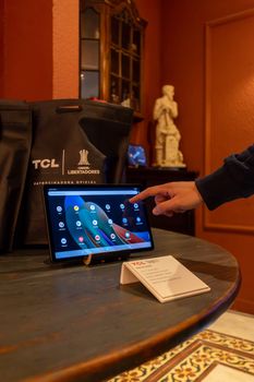 Person demonstrating a TCL tablet with a touchscreen interface in a showroom setting.