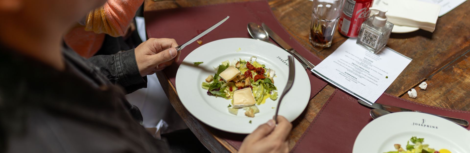 People enjoying a meal with salad dishes in a cozy restaurant setting.