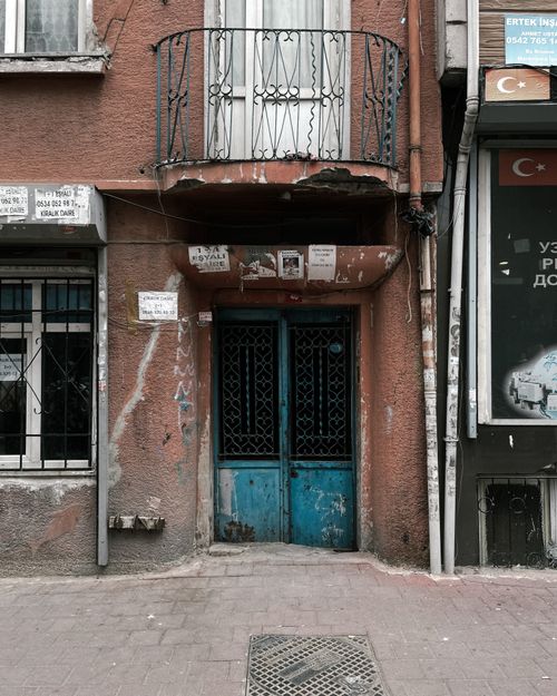 Free A worn building facade showcasing age and urban decay with broken balcony and doorway. Stock Photo