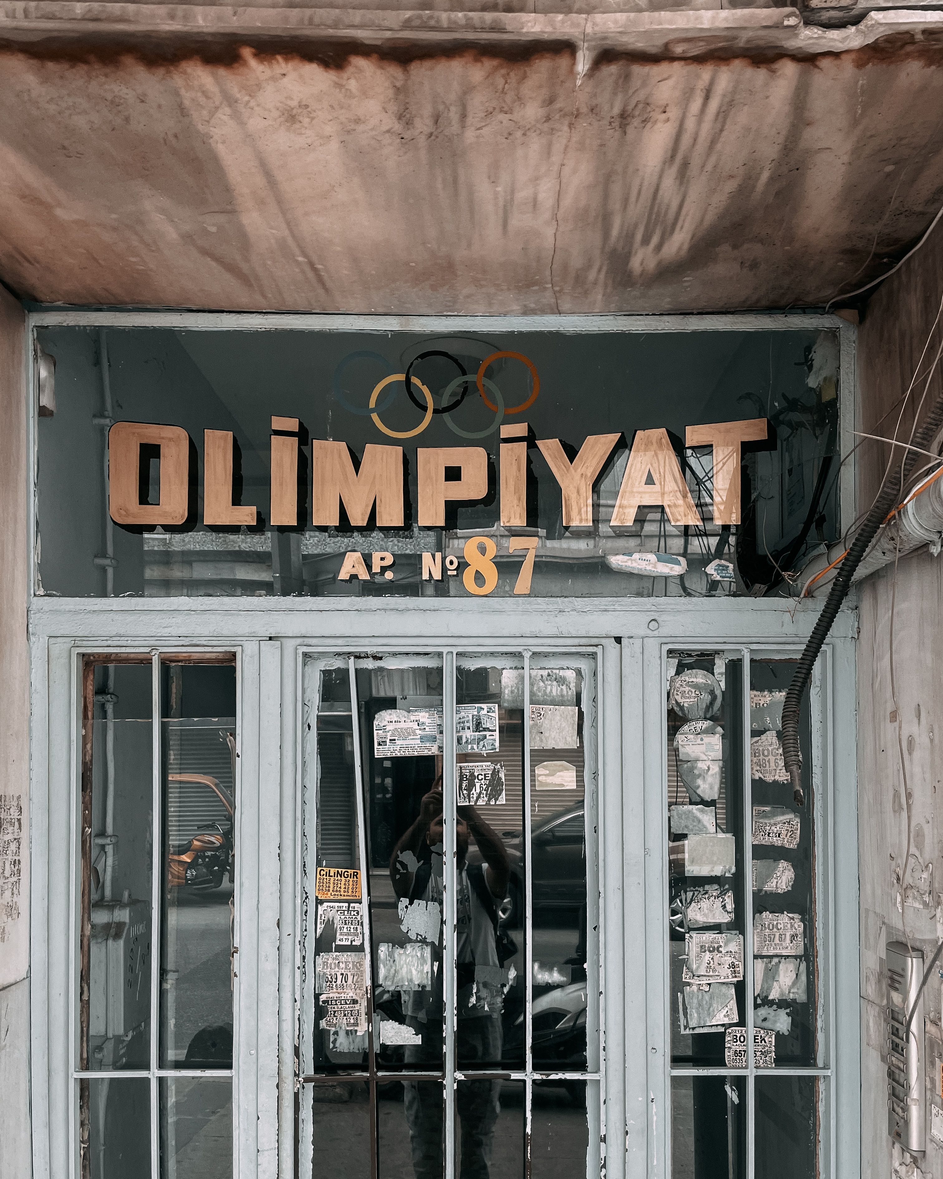 A detailed shot of an urban entrance with reflective glass doors and Olympic-themed signage.
