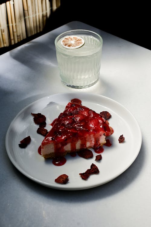 A slice of strawberry cheesecake with a glass of wine