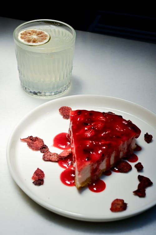 A slice of strawberry cheesecake with a glass of lemonade