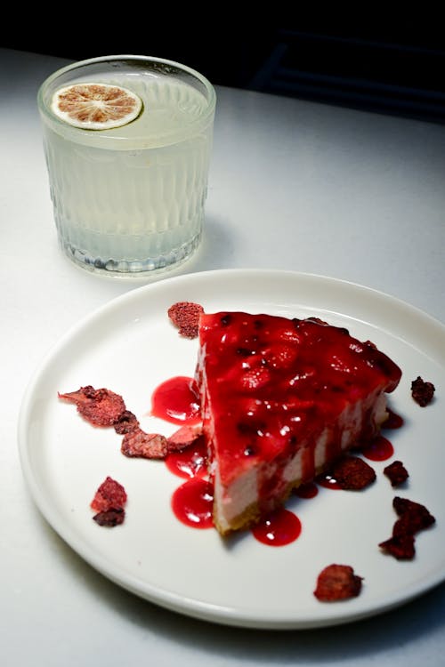 A slice of strawberry cheesecake with a glass of lemonade