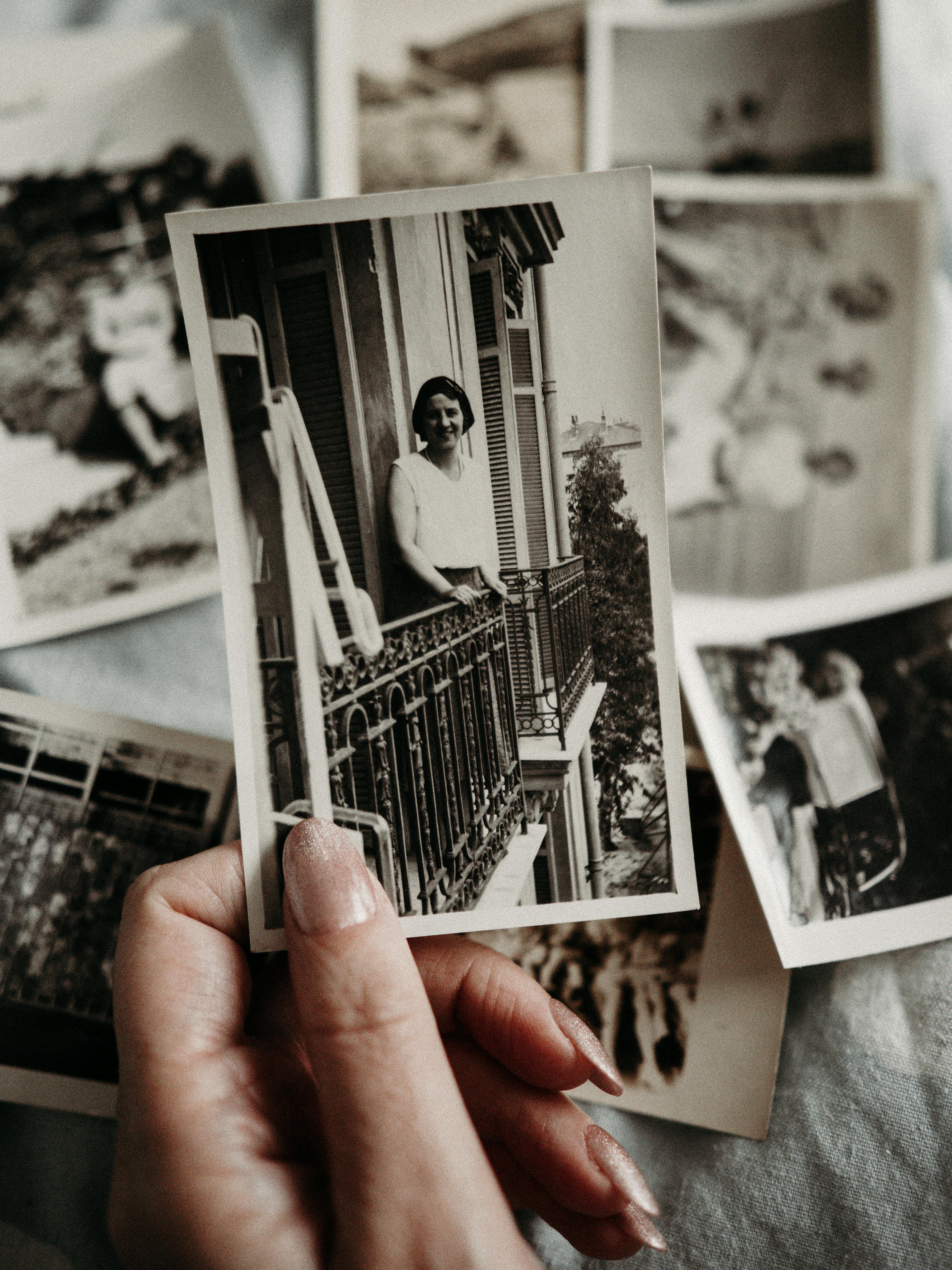 Hand holding a collection of vintage black and white photographs, evoking nostalgia and retro vibes.