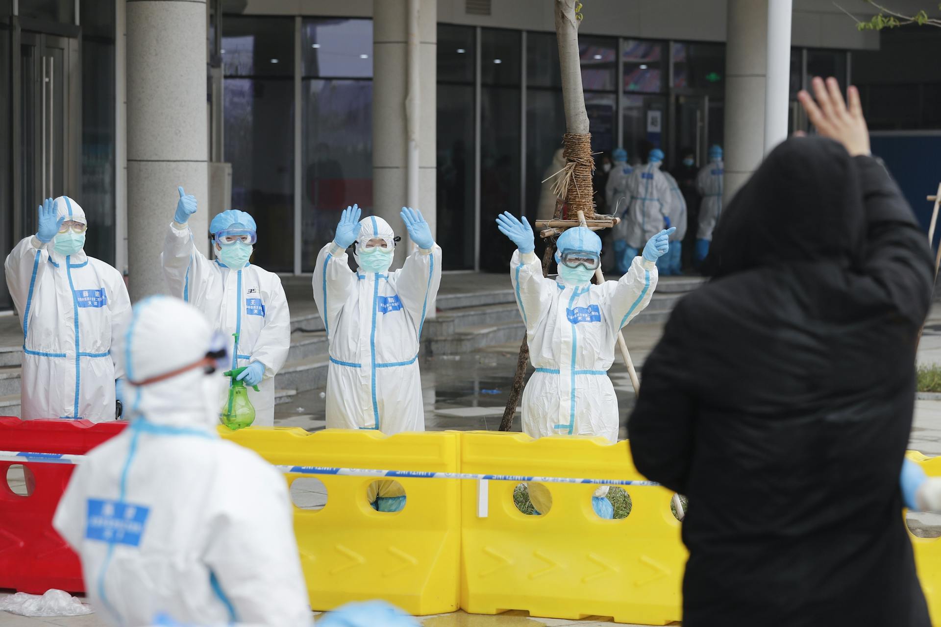 Healthcare professionals in protective gear wave from Wuhan, China during COVID-19.