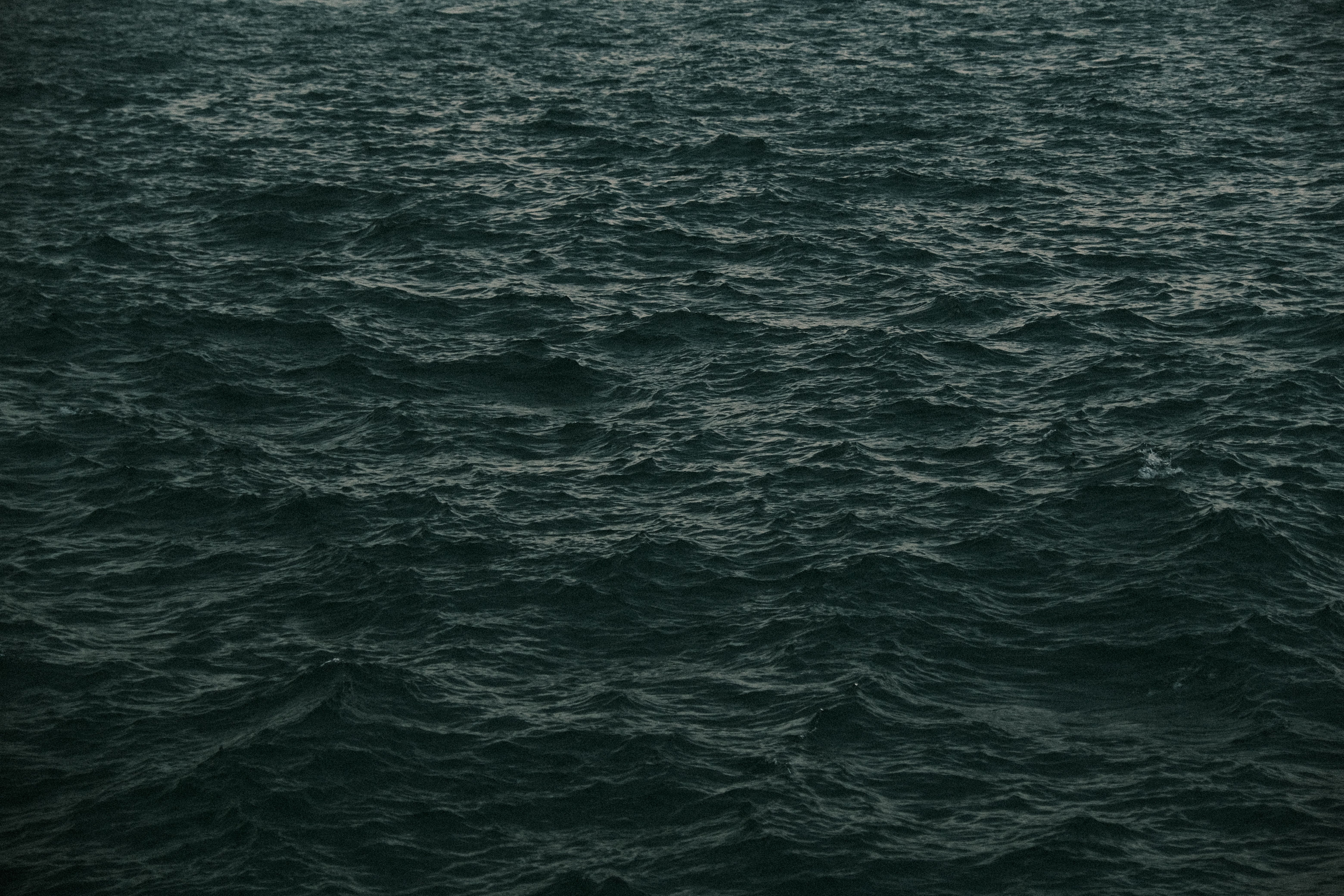 Dark and moody ocean waves captured under an overcast sky, emphasizing texture and movement.