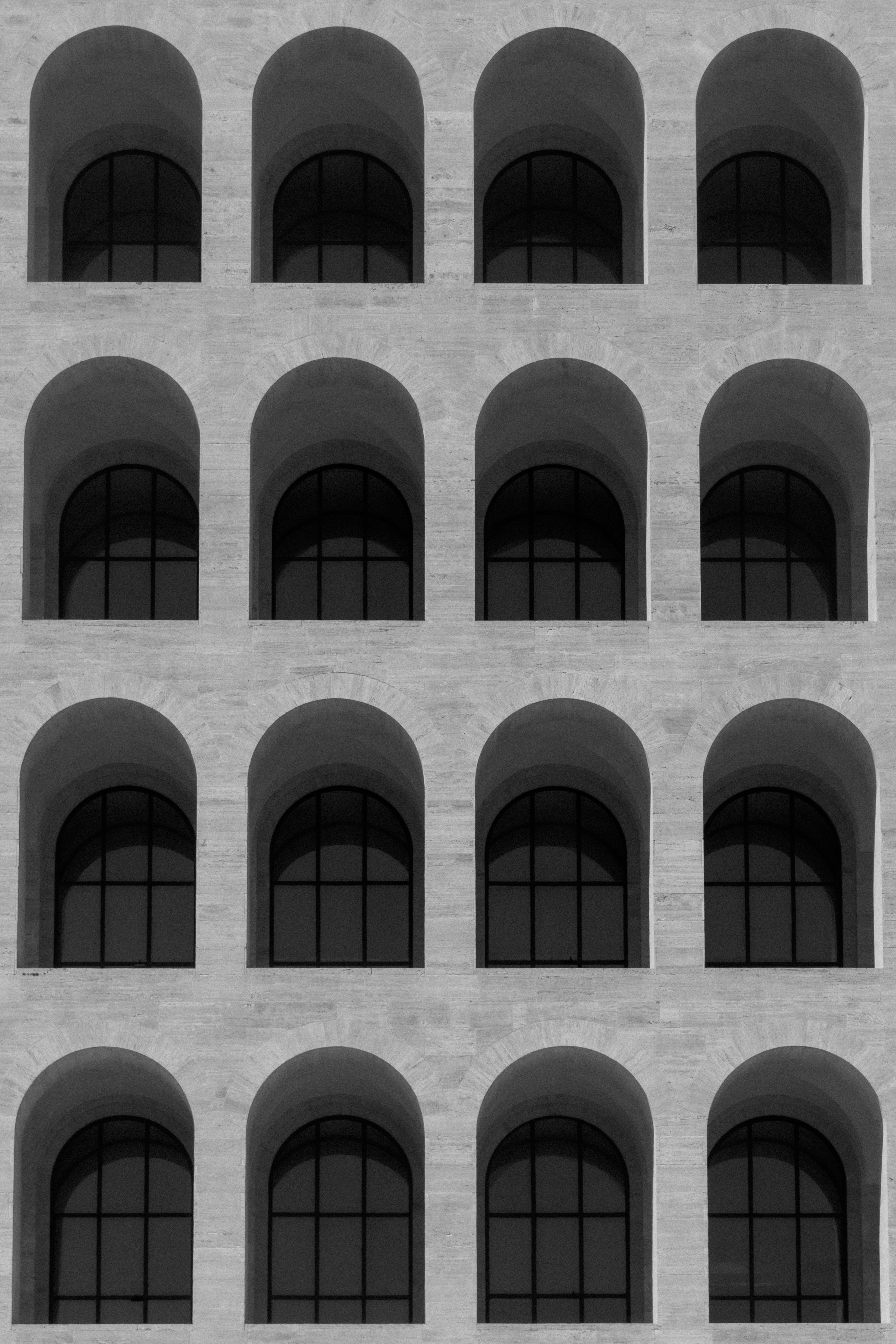 Black and white image of a modern building facade with symmetrical arched windows.