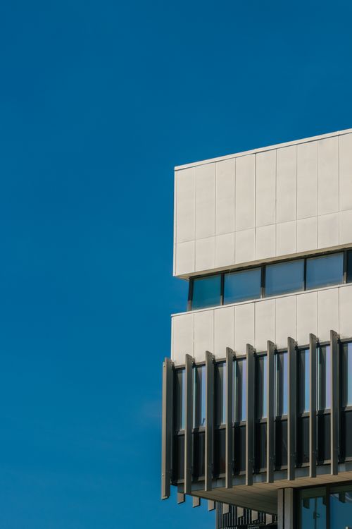 Free Close-up of a contemporary building exterior with a clear blue sky backdrop. Stock Photo