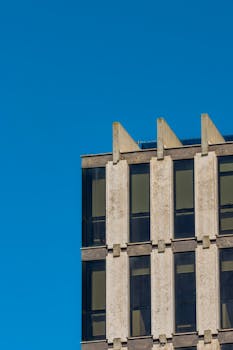 Close-up of a modern office building facade with clear blue sky.