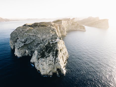 Breathtaking drone shot of rocky cliffs and tranquil sea at sunrise in Spain.