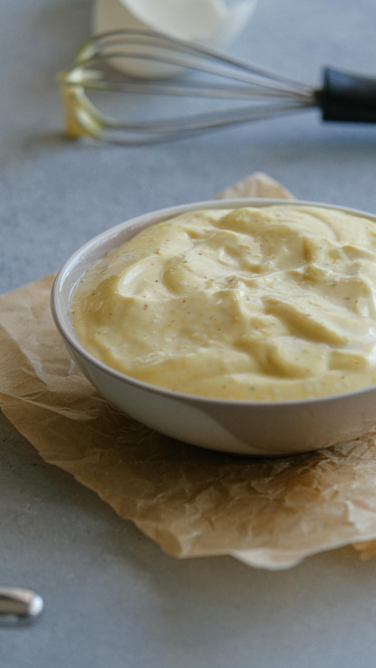 Bowl of creamy mustard sauce on parchment paper