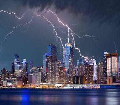 夜晚，繁华的城市天际线笼罩在令人兴奋的雷暴中，海滨倒影令人惊叹