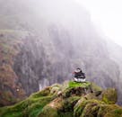在雾气缭绕的法罗群岛迈金斯悬崖上，栖息着一只孤独的大西洋海雀