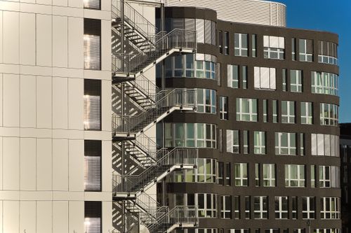 Free A contemporary building facade with steel staircases and glass windows under clear skies. Stock Photo