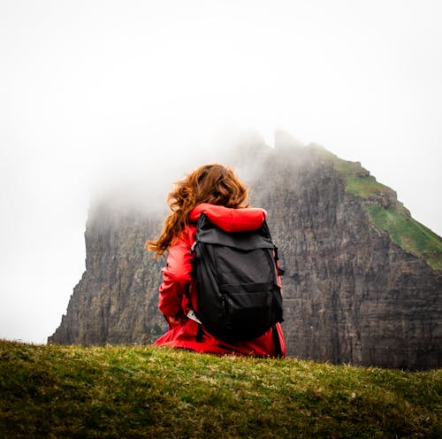 Back View of a Woman Carrying a Backpack Across the Mountain Covered by Clouds