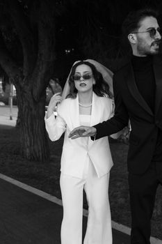 Elegant black and white photo of a fashionable couple in suits and accessories.