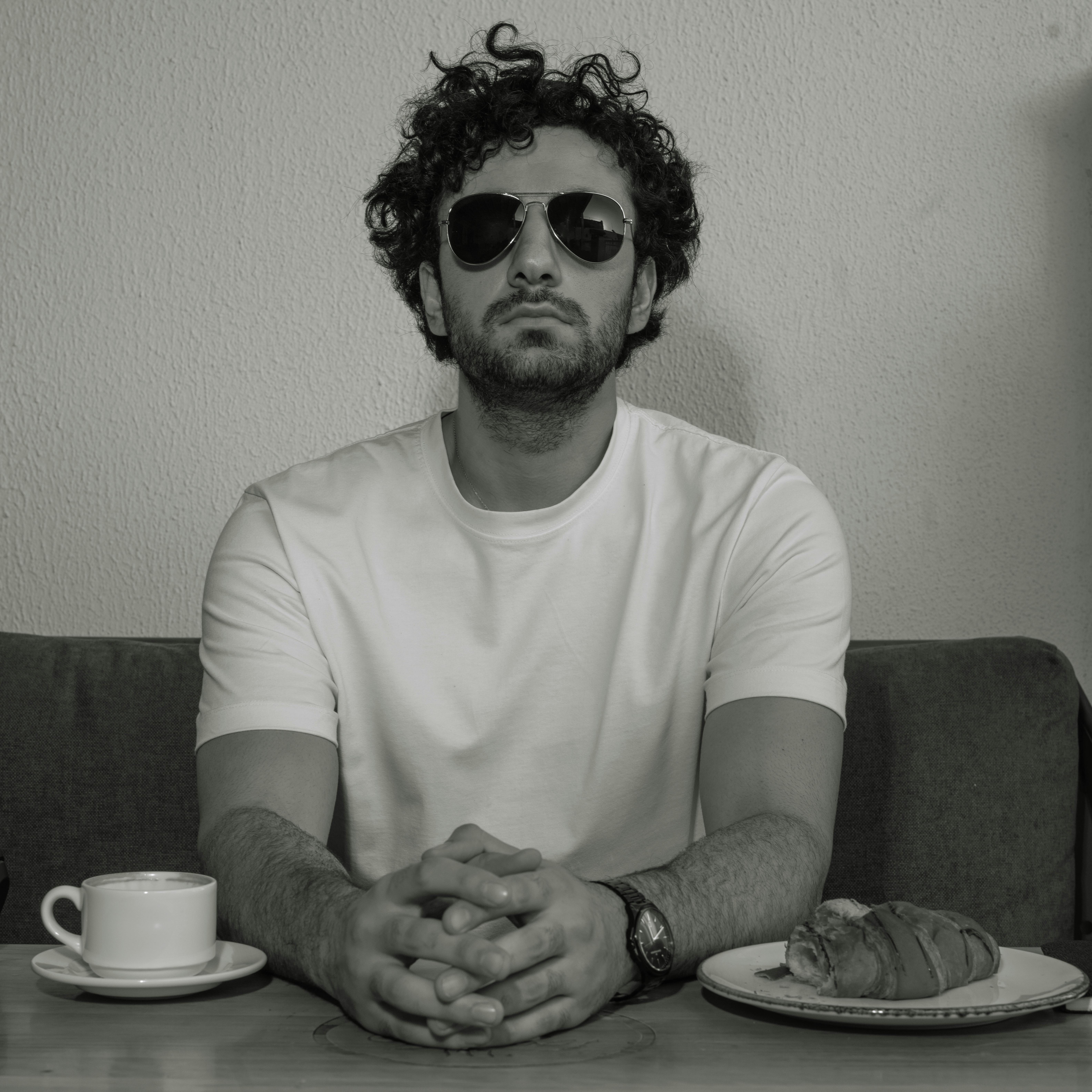 Man in sunglasses enjoying coffee and croissant at a café in Baghdad.