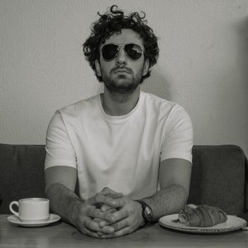 Man in sunglasses enjoying coffee and croissant at a café in Baghdad.