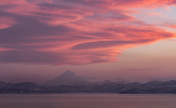 Mesmerizing view of Vilyuchinsky Volcano at sunset with vibrant pink clouds over Kamchatka mountains.