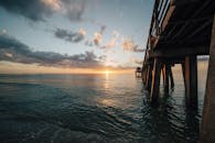 日出时分，宁静的海景中有一座木码头，海水倒映着它的身影