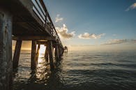 宁静的海边日落中，阳光透过木码头洒下，营造出静谧的氛围