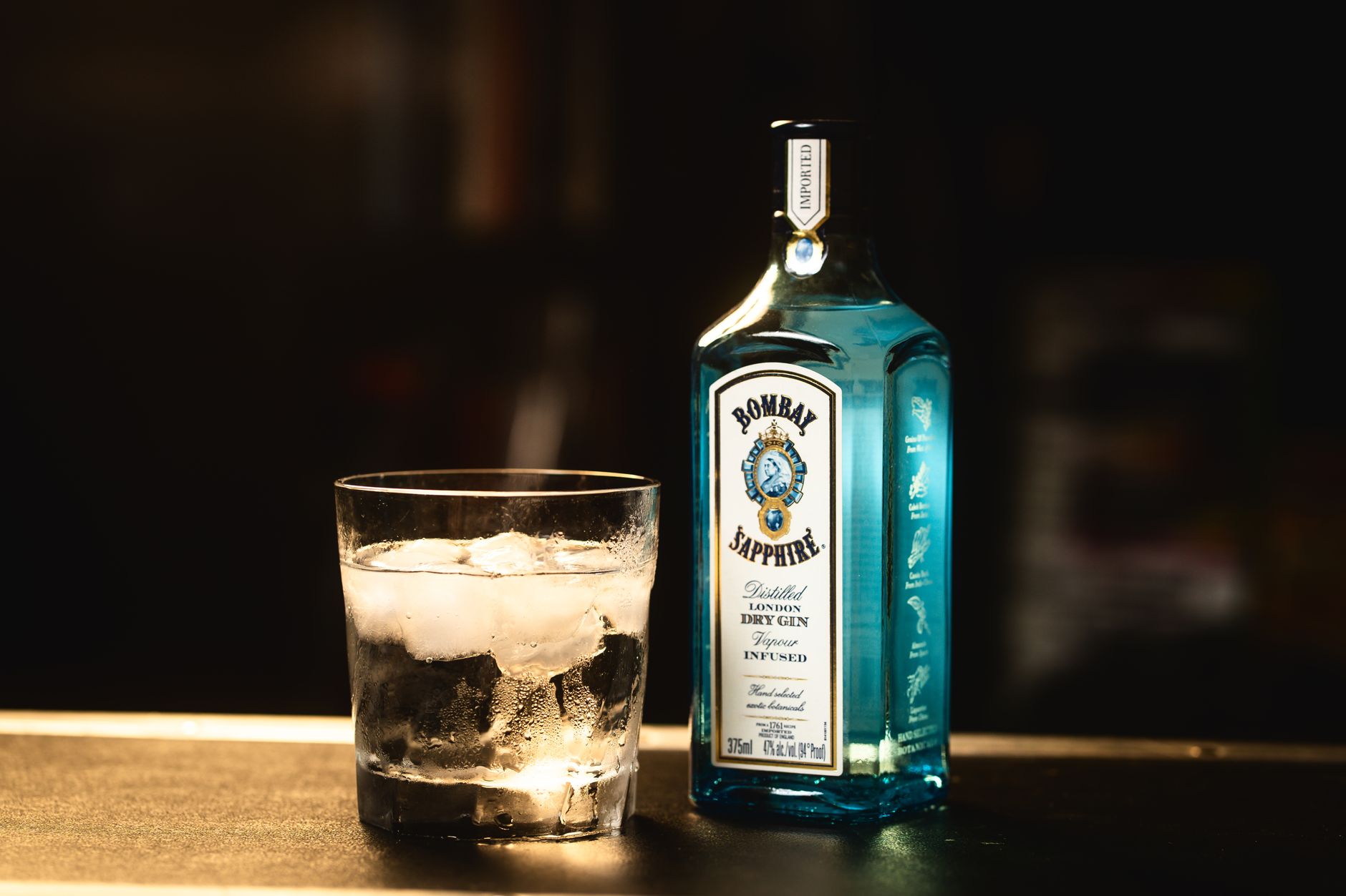 A crystal glass of clear Japanese gin with a minimalist bottle displayed on a dark surface, exemplifying traditional craftsmanship.