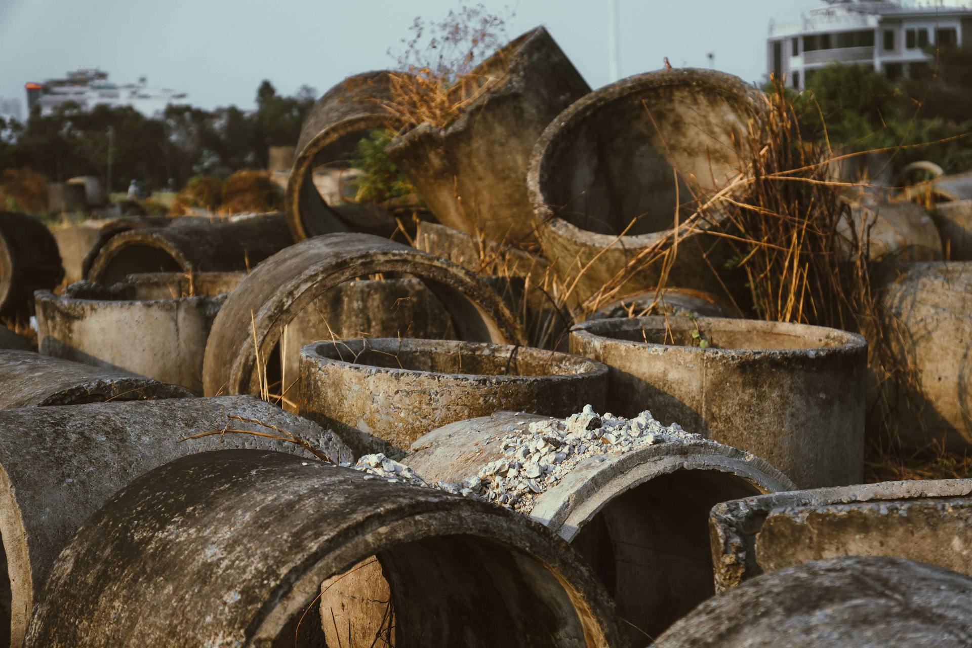 A collection of large weathered concrete pipes abandoned in an outdoor area in Ho Chi Minh City.