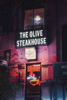 Illuminated neon signs outside The Olive Steakhouse at night, Ho Chi Minh City, Vietnam.