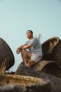 Asian man sitting thoughtfully among concrete pipes in Ho Chi Minh City.